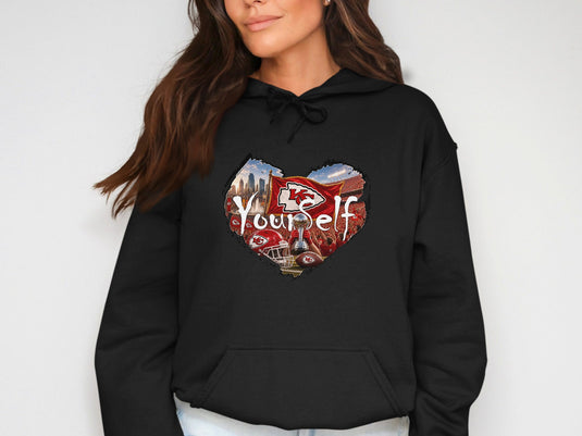 Black hoodie with heart graphic featuring Kansas City Chiefs flag, trophy, and cityscape.